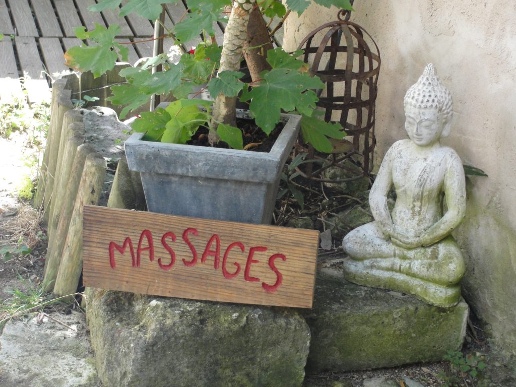 Panneau « Massages » et statuette de Bouddha dans le jardin